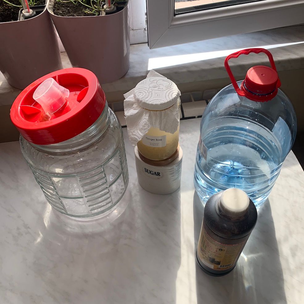 Ingredients for rye kvass: fermentation glass jar, sugar container, bottle of water, bottle of kvass wort concentrate, glass jar containing ginger bug.